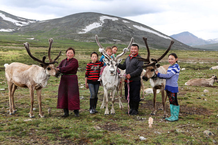 Full family posing proudly with some of their reindeer