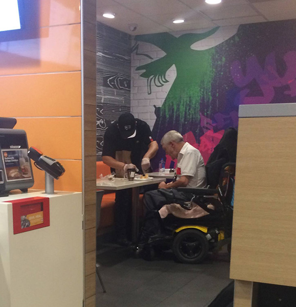 Un angajat McDonald îl ajută pe un bărbăt în vârstă cu mâncarea lui