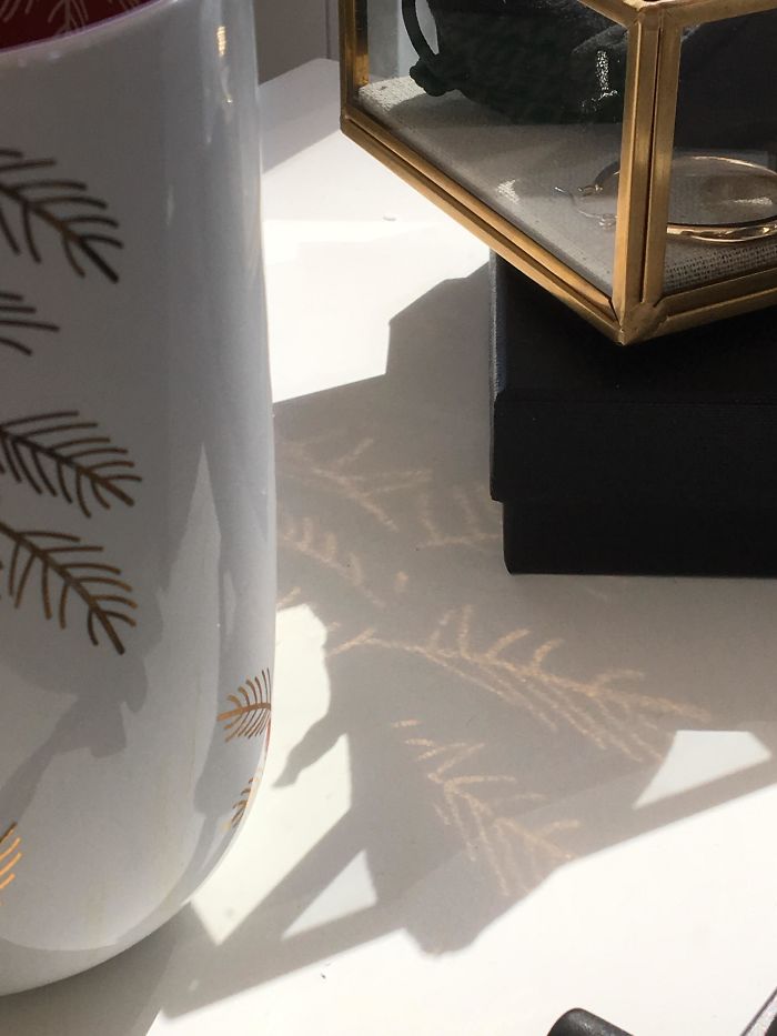 The Gold Designs On This Mug Being Reflected Onto Shadows
