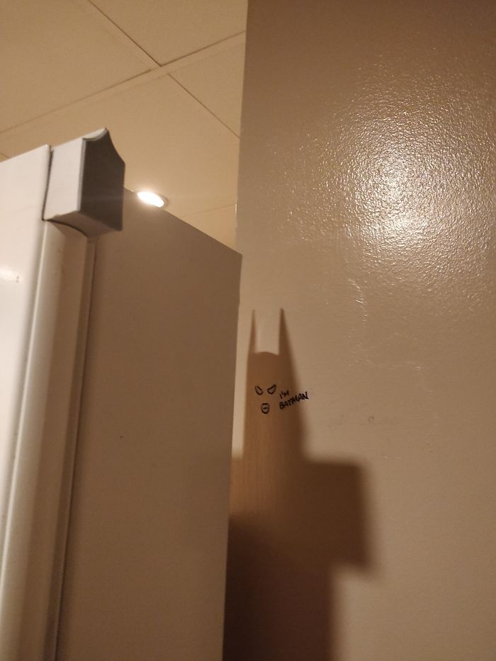 This Urinal Divider's Shadow Looks Like Batman And Someone Drew His Eyes/Mouth