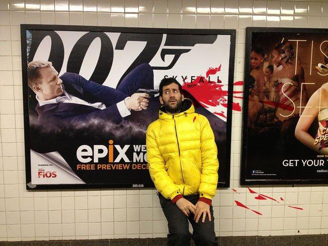 Artist Poses Next To Movie Ads To Raise Awareness Of Violent Imagery In Public Spaces