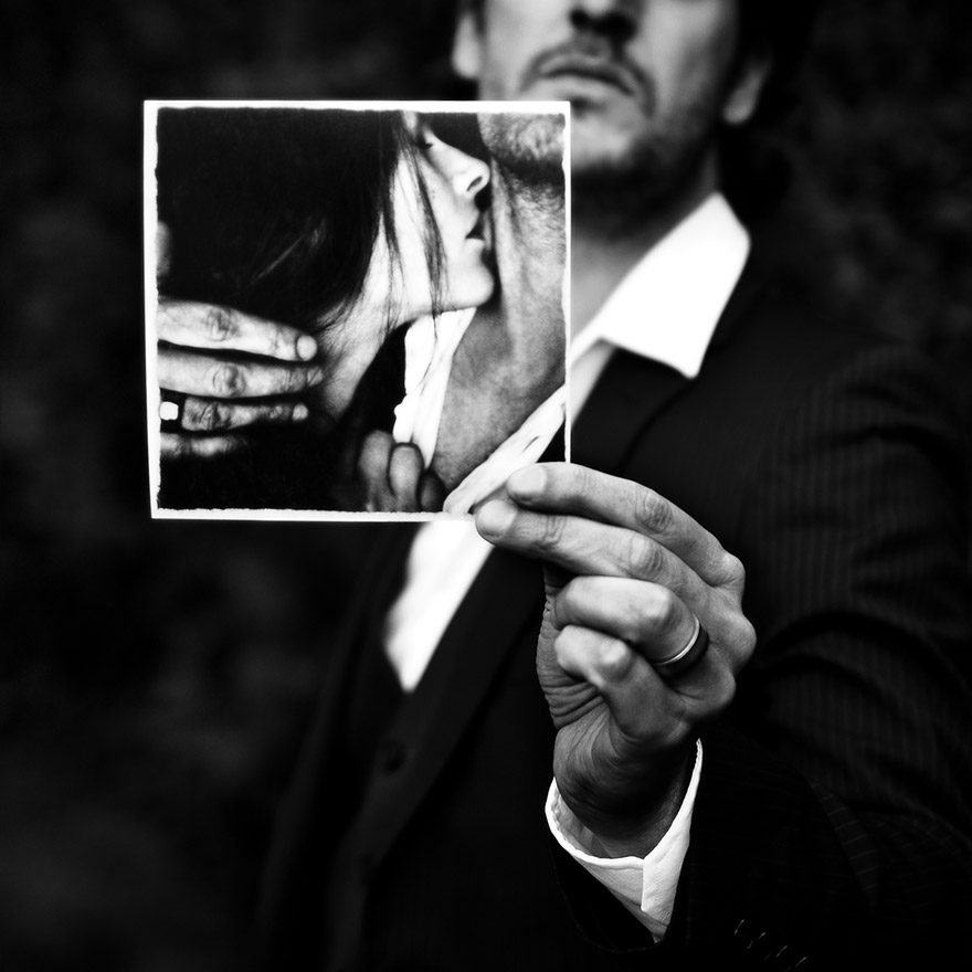 a man holding a photo on which a woman trying to touch the man's neck
