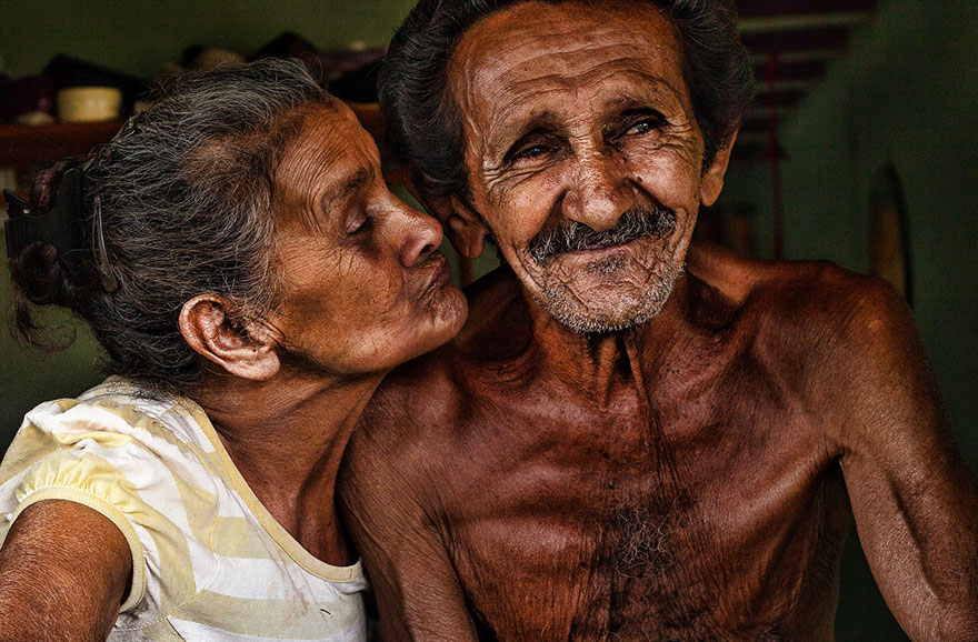 an old woman trying to kiss an old man into his cheek