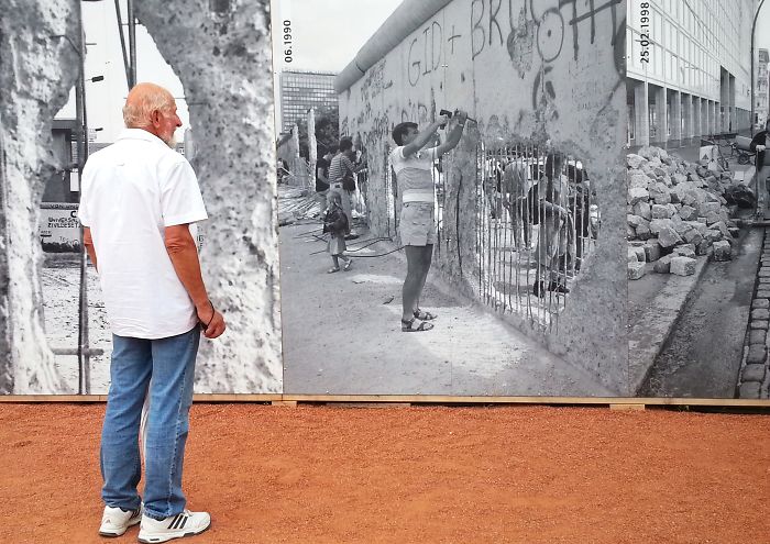 Man Looking At Pictures Of The Berlin Wall.