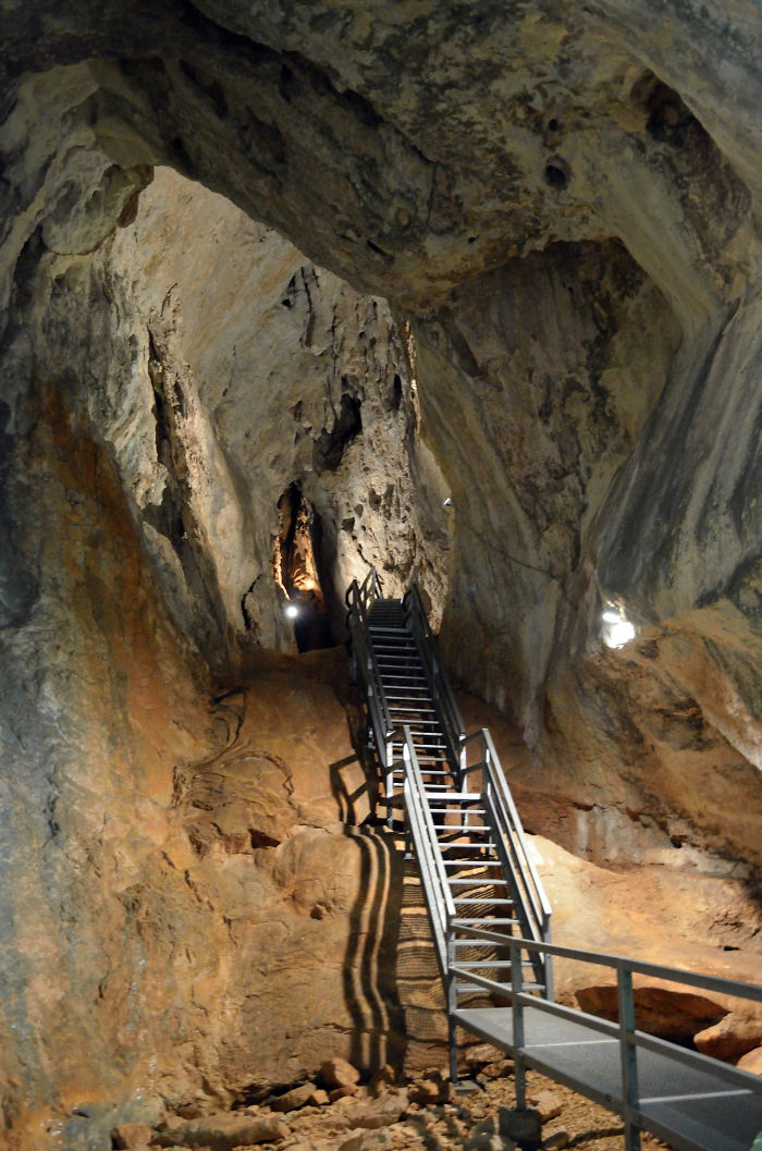 Metal staircase inside a beautiful cave with rugged rock formations and ambient lighting showcasing natural cave beauty.