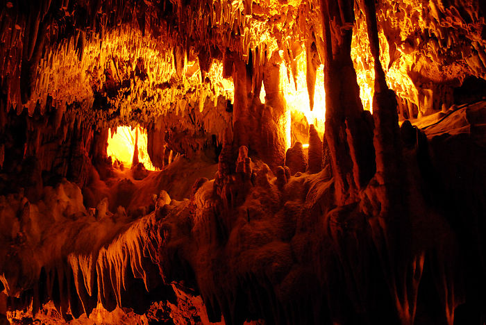 Glowing interior of a beautiful cave with intricate stalactites and stalagmites illuminated by warm light.