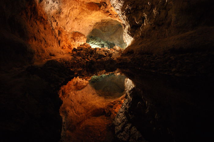 Interior view of a beautiful cave with natural rock formations and water reflections inside a dark cavern.