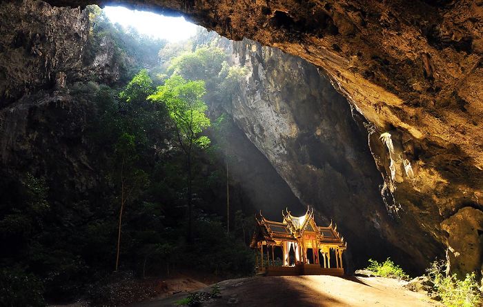 Beautiful caves from around the world with sunlight streaming through a large cave opening onto a temple inside.