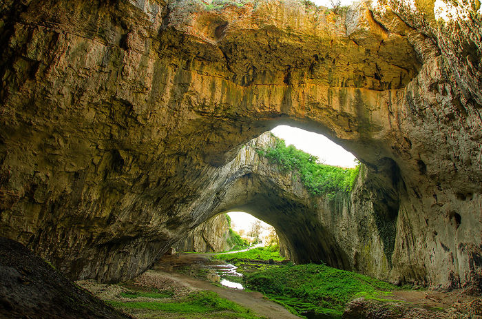 Natural rock formations create beautiful caves with sunlight illuminating greenery inside the scenic cave openings.