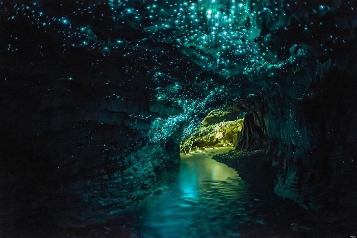 Glowing blue cave interior with sparkling light effects and a narrow water path, showcasing beautiful caves worldwide.