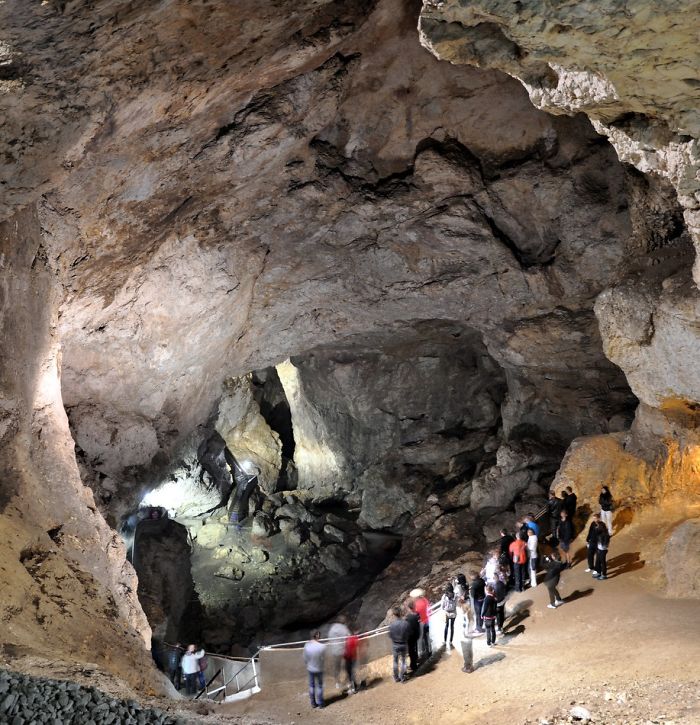 Visitors exploring a large beautiful cave with rocky walls and natural formations inside a popular cave destination.