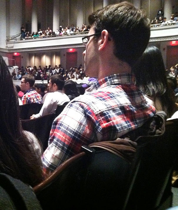 Two man sitting at the concert and wearing similar shirts