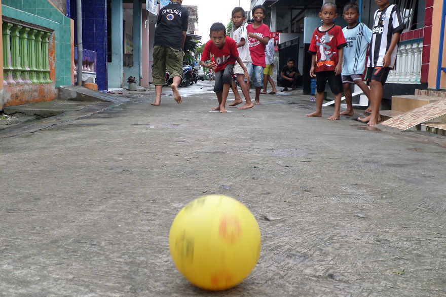 Indonesian Kids Playing Plastic Footbal On The Street.