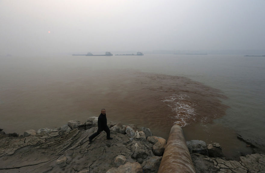 Man Walks By Pipe Discharging Waste Water Into Yangtze River