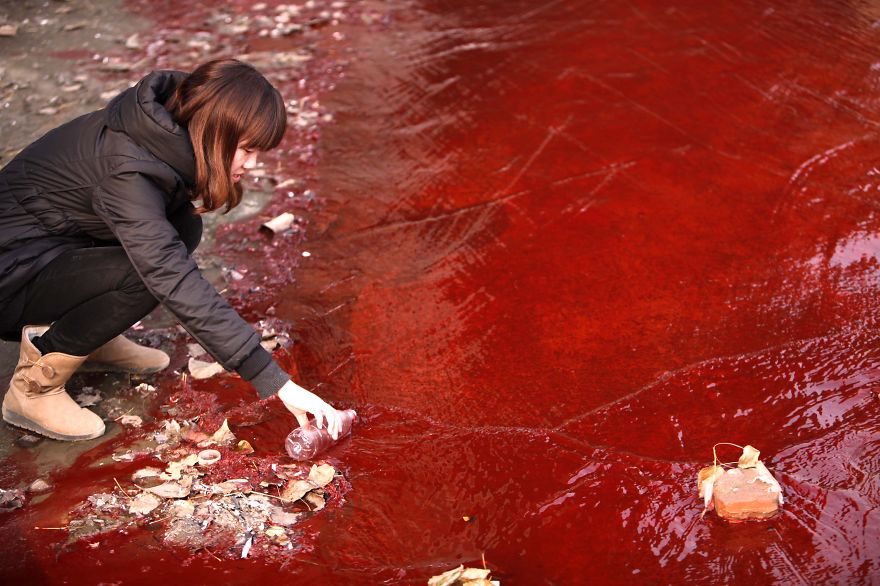 Journalist Takes A Sample Of Red Polluted Water From The Jianhe River