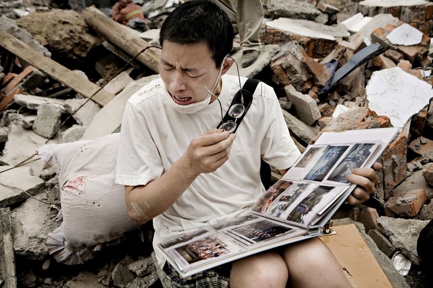A Man Cries While Flipping Through A Family Album He Found In The Rubble Of His Old House