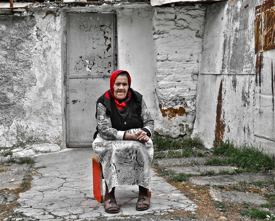An Old Romani Woman Sitting In Front Of Her House In Tirana, Albania