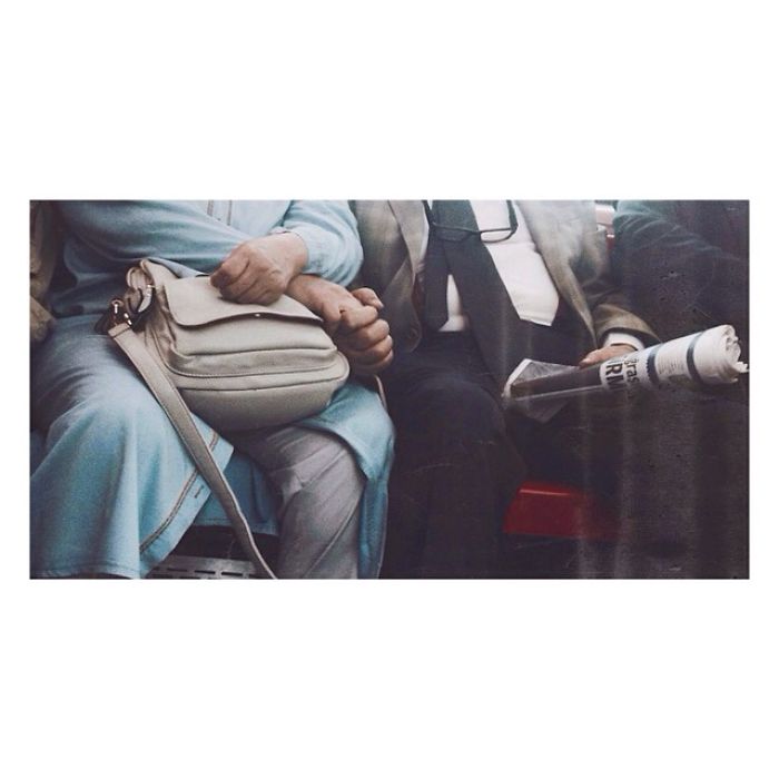 Elderly couple holding hands on a bench, conveying warmth and connection through a simple gesture.