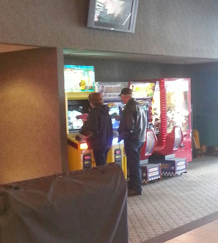Elderly couple enjoying arcade games, highlighting that you're never too old to have fun.