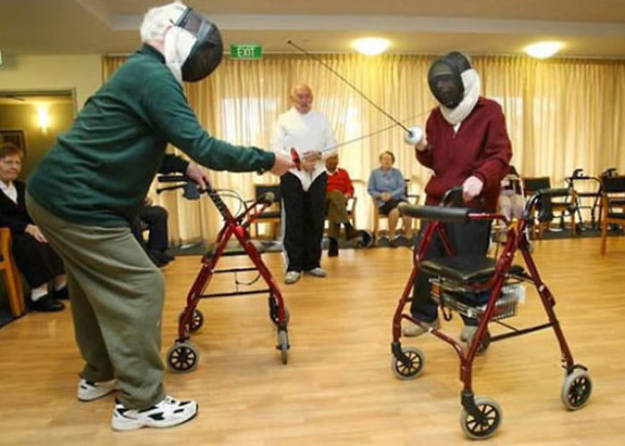 Elderly couple having fun fencing with walkers in a community center.
