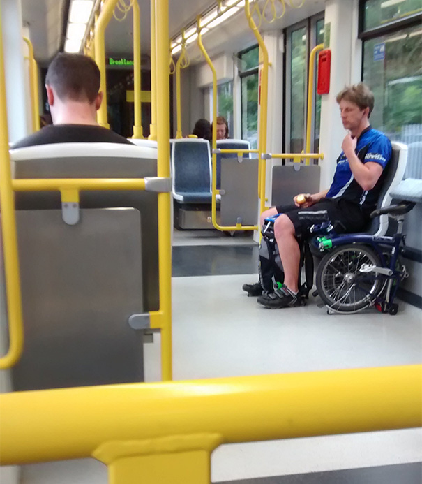 This Guys Folded Bicycle Makes Him Look Like He's Sitting In A Wheel Chair Whilst On The Tram