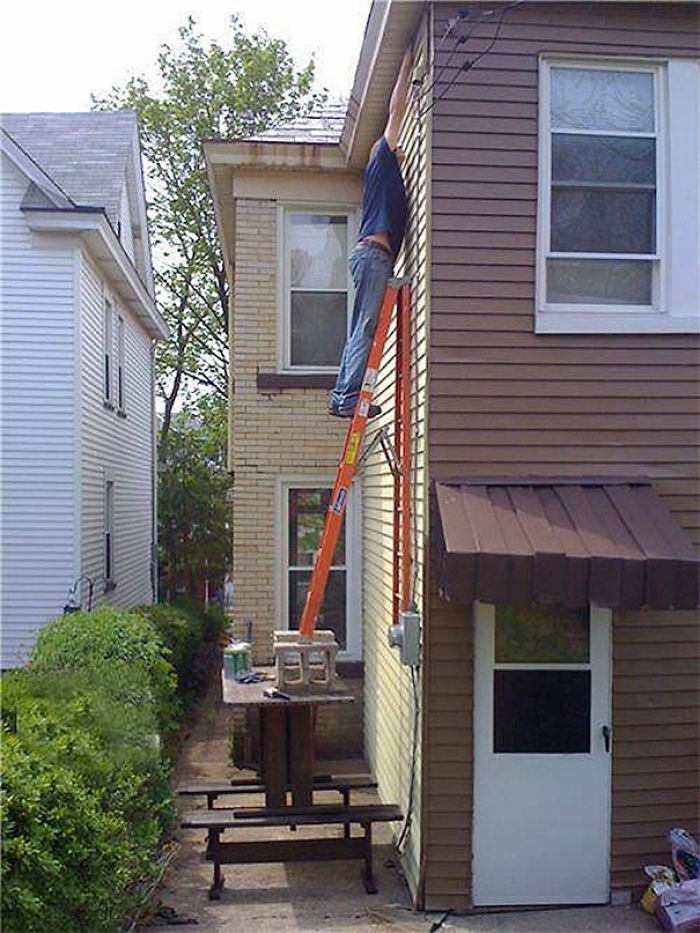 Man dangerously reaching from ladder on a patio table, illustrating risky behavior related to lifespan differences.