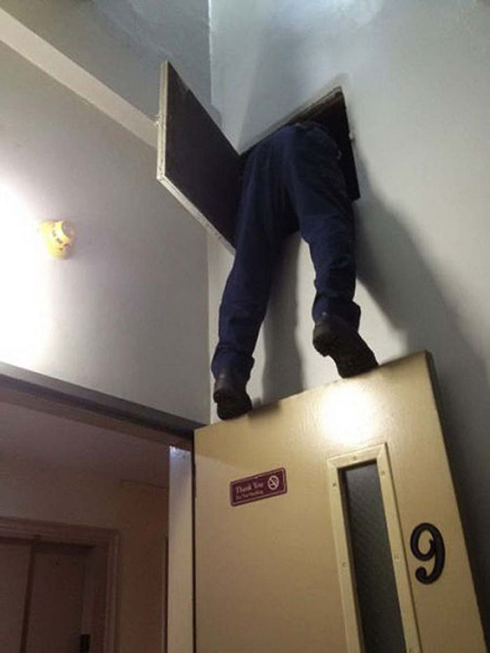 Man precariously climbing through a narrow wall opening, illustrating why women live longer than men.
