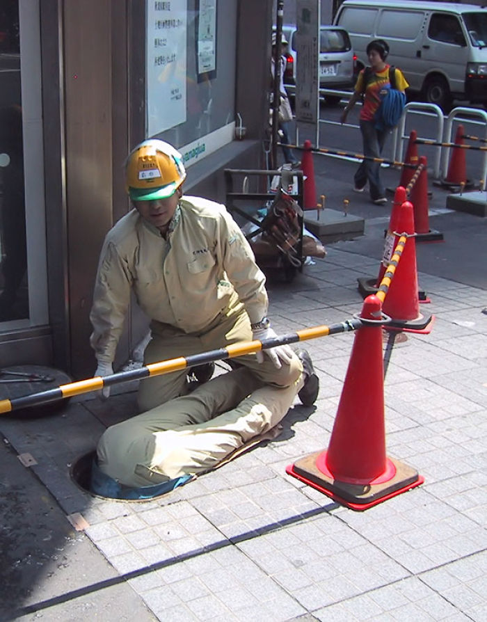 Worker entering a manhole with caution cones nearby, illustrating reasons why women live longer than men.