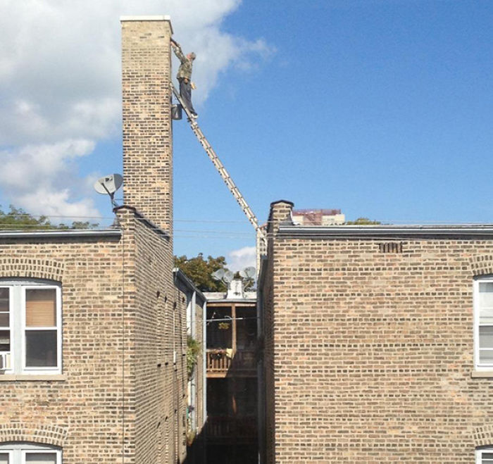 Man precariously on a ladder between buildings, illustrating why women live longer than men.