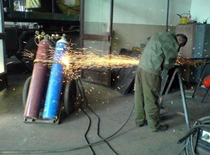 Man welding near gas cylinders, safety concerns highlight reasons women live longer.