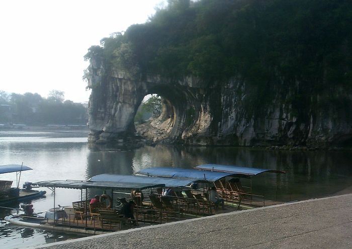 Boats docked by the river with Elephant Trunk Hill rock formation in Guilin, a top travel destination in China.