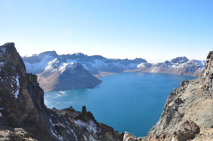 Scenic view of a blue lake surrounded by snow-capped mountains highlighting reasons to visit China’s natural beauty.