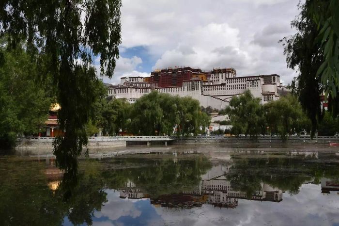 Potala Palace in China surrounded by trees and reflected in water, showcasing iconic travel destination and cultural heritage.
