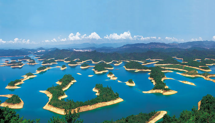 Aerial view of scenic islands and blue waters surrounded by green hills, showcasing natural beauty for visit China travel.