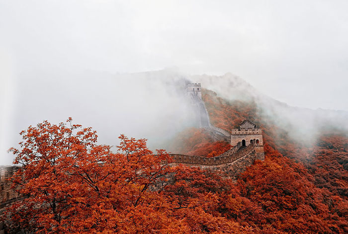 Great Wall of China surrounded by autumn foliage and mist, showcasing why you should visit China for its stunning landscapes.