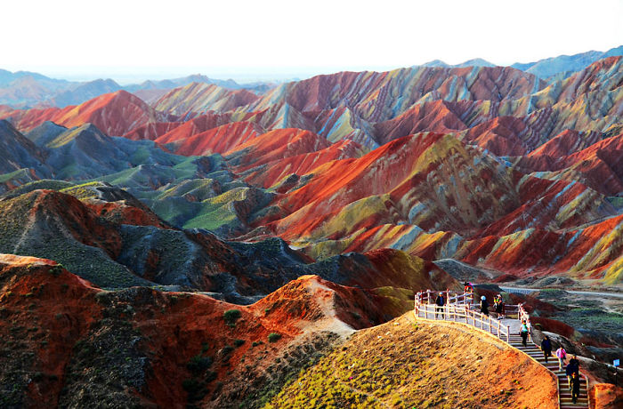Colorful Zhangye Danxia landform in China with tourists exploring the scenic, unique geological formations and vibrant mountains.