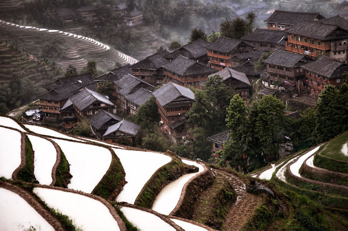 Traditional village nestled among lush green terraces showcasing reasons to visit China’s scenic rural landscapes.