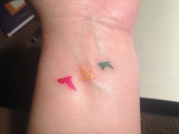 Three little red, yellow, green Rasta birds tattoo on wrist