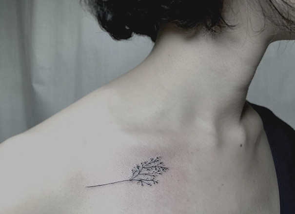 Delicate flower branch tattoo near the collarbone