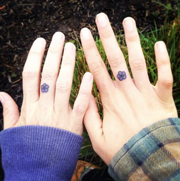 Minimal blue flowers matching tattoos on a couple fingers
