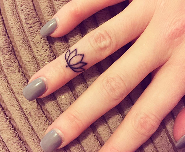 Black minimal lotus flower finger tattoo