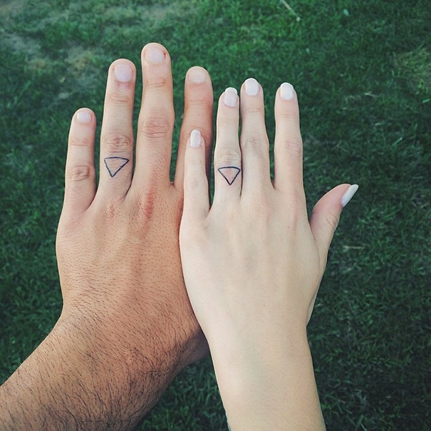 Matching water triangle symbol tattoos on a couple fingers