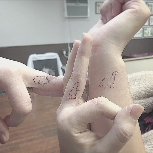 Three hands with simple linear dinosaur tattoos