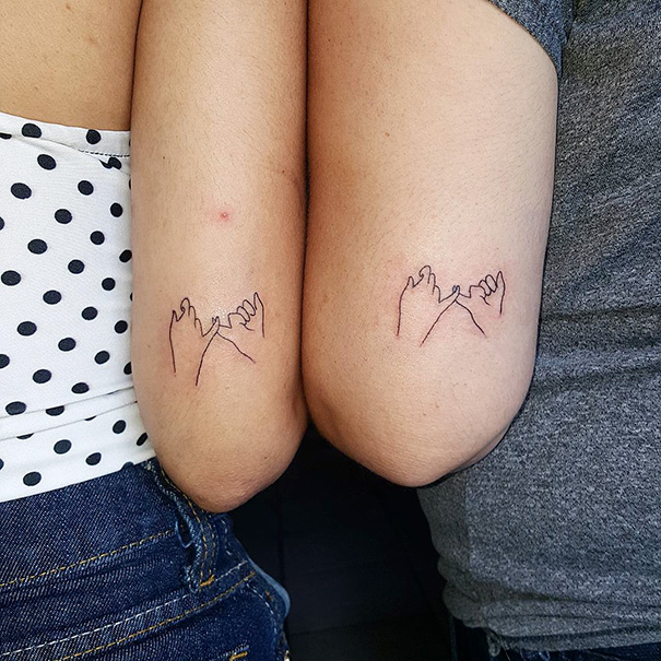 Two persons with minimal, linear two hands hook little fingers together tattoos their arms