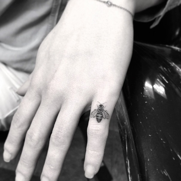 Bee tattooed on small left-hand finger