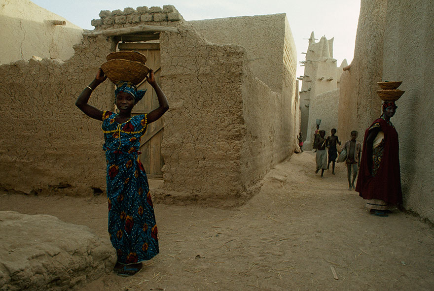 Women Carry Baskets On Their Heads While Children Play In Kotaka, Mali, 1991