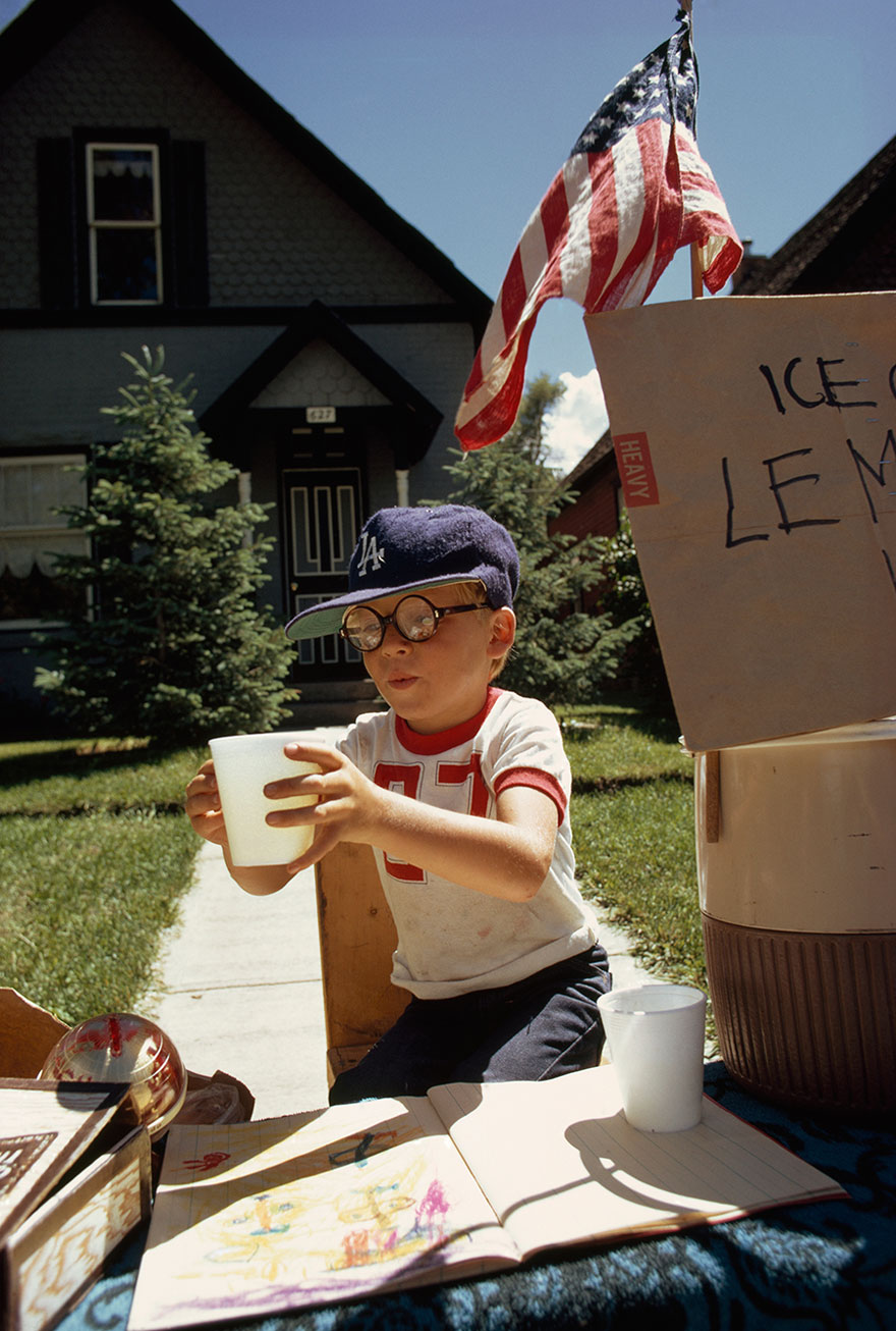 A Boy Sells Lemonade From His Front Yard Stand On Main Street In Aspen, Colorado, 1973