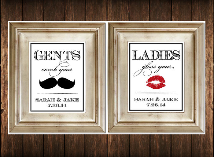 Two framed funny bathroom signs for gents and ladies with mustache and lipstick graphics on wooden wall.
