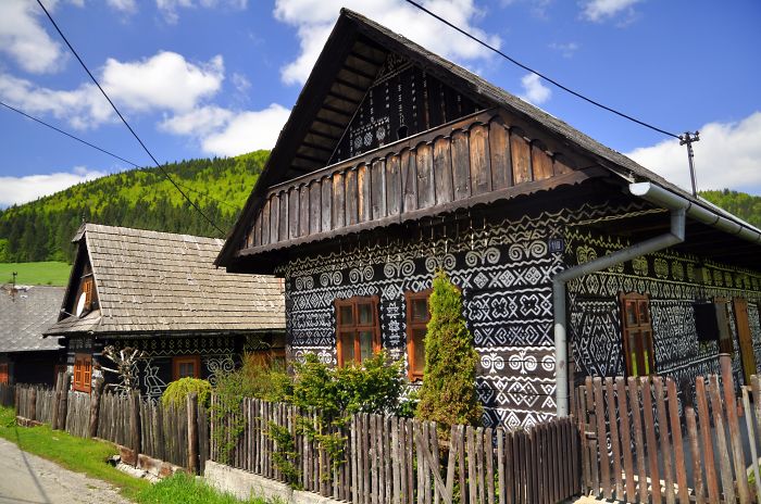 Fairy tale village with traditional wooden houses and intricate patterns, nestled in a lush green landscape.
