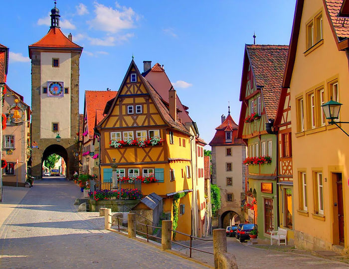 Fairy tale village scene with colorful half-timbered houses and a historic tower.